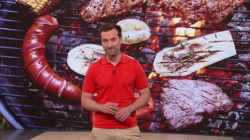 Daniel Aßmann steht im Servicezeit-Studio. Im Hintergrund sieht man die Abbildung eines Grills.