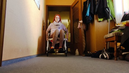 Annika Witteler sitzt im Rollstuhl in ihrem Wohnzimmer. 