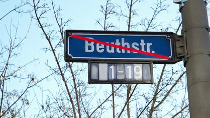 Straßenschild auf dem der Straßenname "Beuthstraße" durchgestrichen ist.