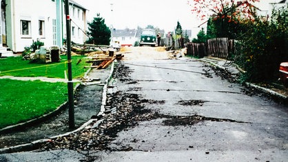 Eine Straße mit Schäden, im Hintergrund steht ein Auto
