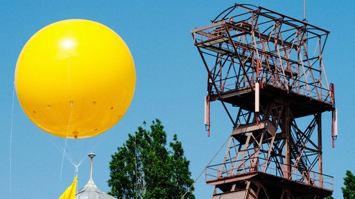 Ein großer gelber Luftballon, im Hintergrund ist der Förderturm einer Zeche zu sehen