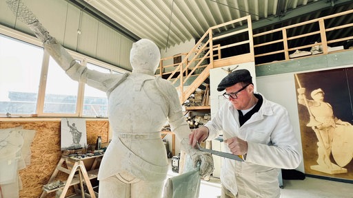 Steinmetzmeister Markus Madeia bearbeitet den Arm einer Ritterskulptur
