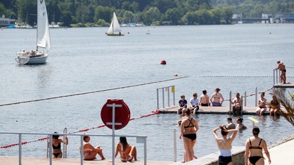 Mehrere Badegäste schwimmen und sitzen an der Badestelle am Essener Baldeneysee. | Bildquelle: dpa/Roland Weihrauch Mehrere Badegäste schwimmen und sitzen an der Badestelle am Essener Baldeneysee.
