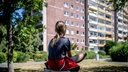 Ein Kind sitzt vor einem Plattenbau