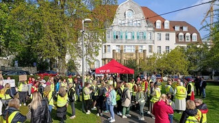Mehrere Menschen mit Warnweste stehen vor dem Uniklinikum in Wuppertal. 