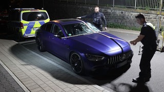 Ein beschädigter Mercedes AMG steht nach einem Unfall auf einer Straße in Remscheid Lennep. Polizeibeamte sichern Spuren an dem Fahrzeug.
