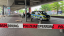 Ein Polizeiauto im Hintergrund. Im Vordergrund ein Absperrband mit der Aufschrift "Polizeisperrung".