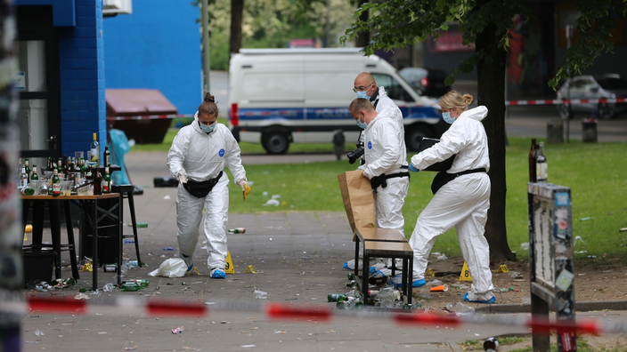 Vier Personen in weißen Schutzanzügen sichern Spuren am Tatort.