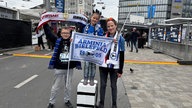 Eine Mutter zusammen mit ihren Kindern, die kleine Tochter steht auf einem selbstgebastelten Styropor-Hocker für das Public-Viewing.