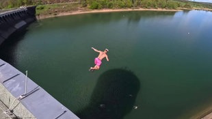 Menschen springen von einem Turm in Wasser