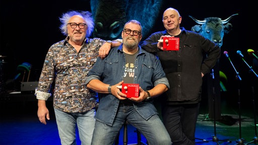 Die Kabarettisten Urban Priol, Jochen Malsmheimer und Frank Goosen posieren lachend auf der Bühne
