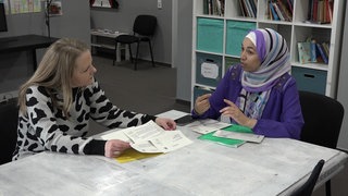 Zwei Frauen, die an einem Tisch sitzen und miteinander reden